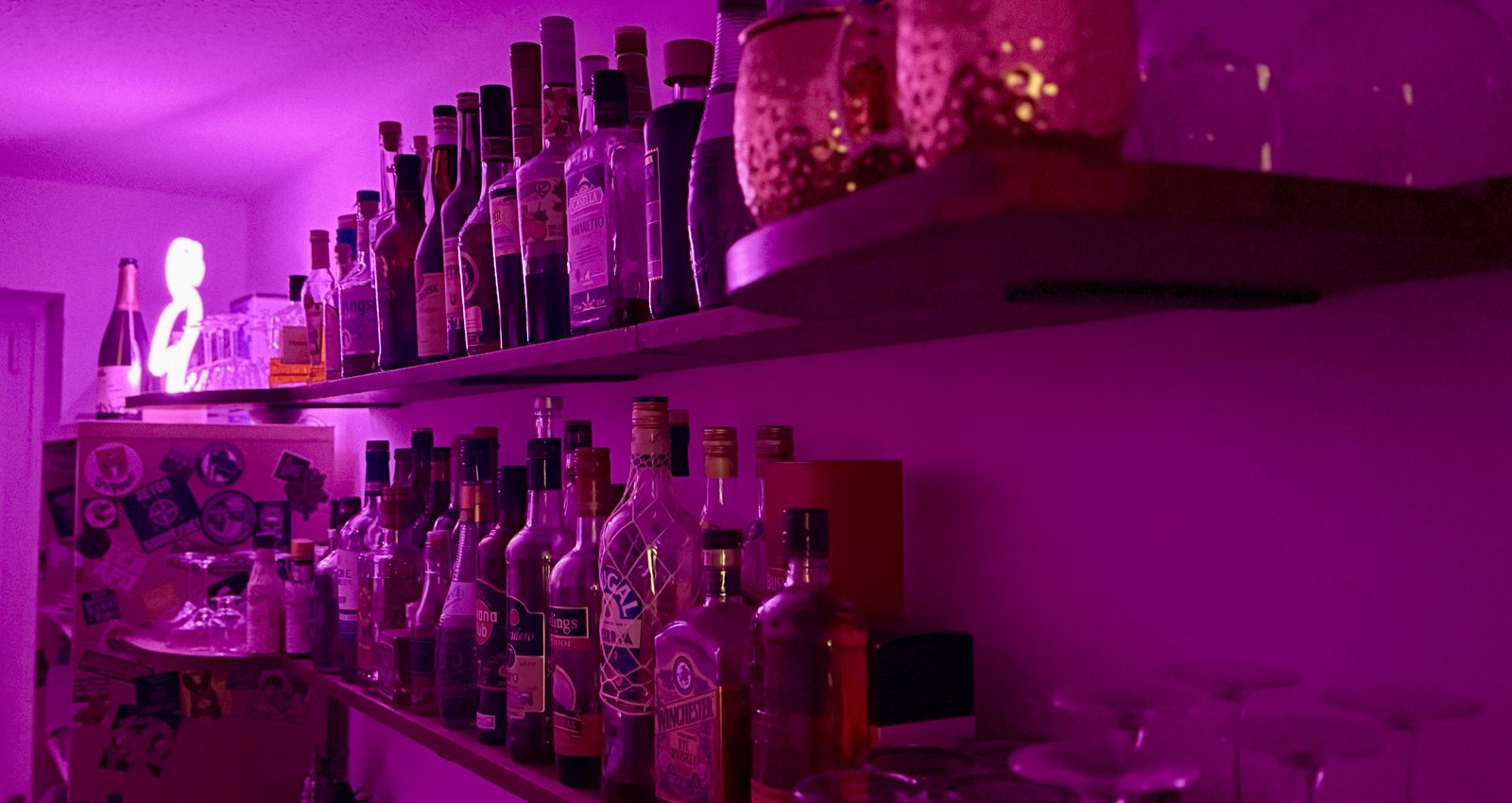 Flaschenregale und Gläser unserer privaten Bar, orange eingefärbt.